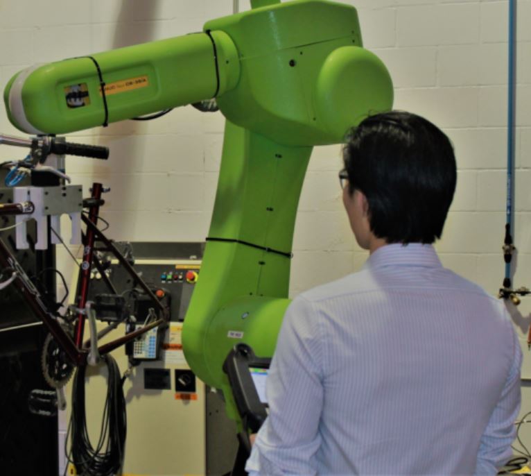 EWI cobot consultant works on a large cobot's arm