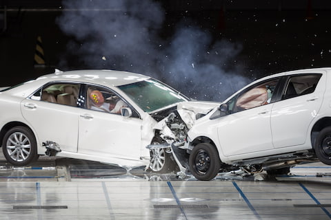 Two white sedans crashing into eachother for a crash test.