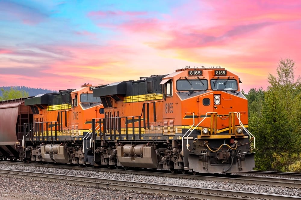 An orange train with a lovely sunset backdrop